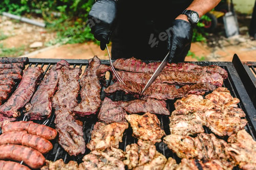 Preview: cook preparing grilled meat during a barbecue.