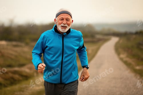 Preview: Motivated mature athlete jogging and listening music on earphones.