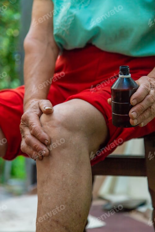 Preview: Grandmother treats her knees, smears the medicine. Selective focus.
