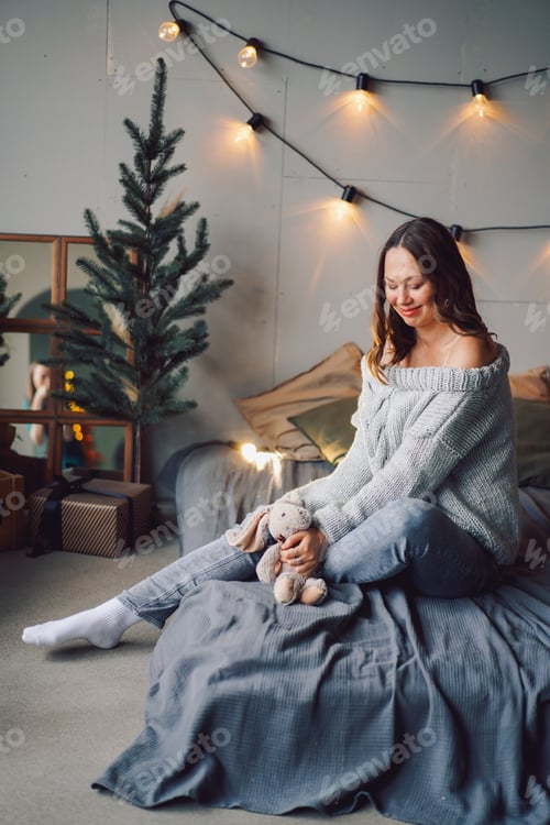 Preview: portrait of a beautiful European girl in the light of Christmas garlands, joyful enjoying home comfo