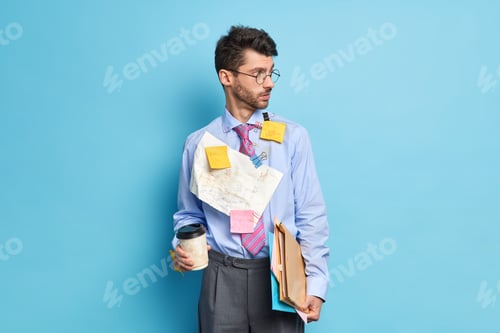 Preview: Horizontal shot of European man manager looks aside with thoughtful expression holds disposable cup