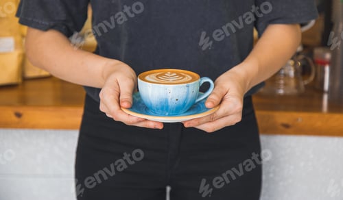 Preview: Elegant woman is holding an art designed coffee latte in her hand