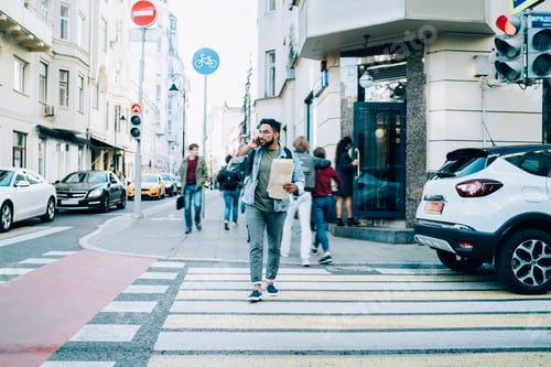 Preview: Man speaking on mobile phone crossing pedestrian passage in city