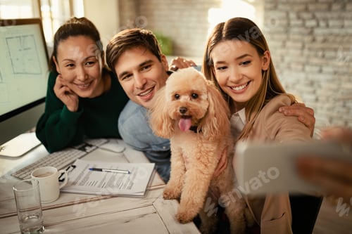Preview: Happy colleagues and their dog taking selfie in the office.