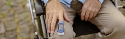 Preview: Close up shot of hand of handicapped man in wheelchair using fingertip pulse oximeter for
