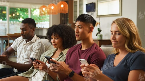 Preview: Group of Friends Engaged With Smartphones While Relaxing in Cozy Living Room During Afternoon