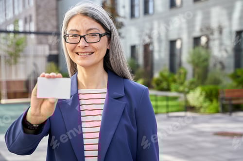 Preview: Mature business lady holding a blank plastic card and smiling