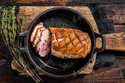 Vista previa: Duck breast roasted in a pan, poultry meat steak with herbs. Wooden background. Top view