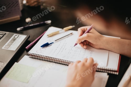 Preview: Close up detail image of a young woman studying and working on his home desk, doing homework
