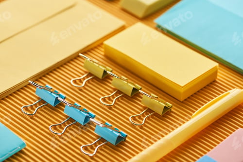 Preview: close up view of colorful office stationery supplies on yellow