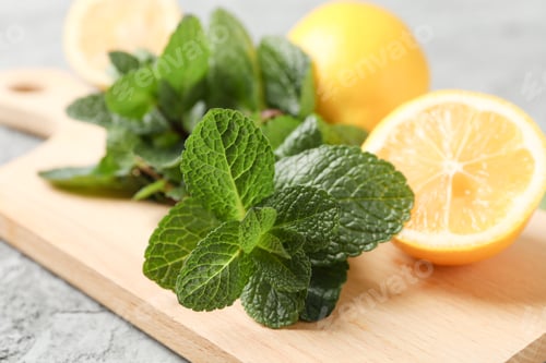 Preview: Cutting board with lemon and mint on grey background, close up