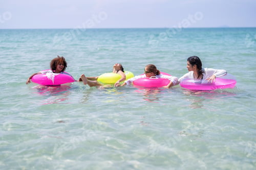 Preview: Teenage girl friendship enjoy laughing play on sea swimming with water inflation toy on blue sky day