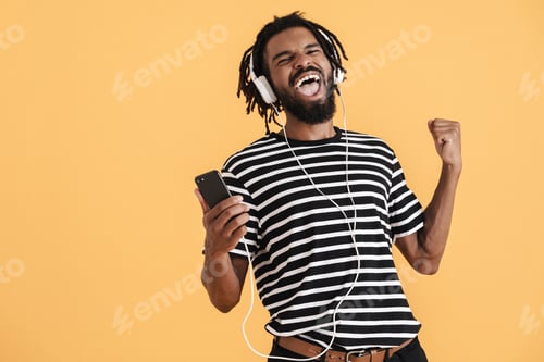 Preview: Photo of african american guy using cellphone and making winner gesture