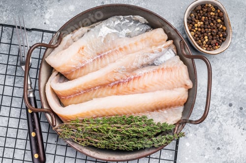 Preview: Raw Hake fish fillet in steel tray with herbs. grey background. top view
