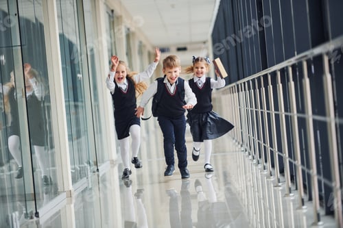 Preview: Active school kids in uniform running together in corridor. Conception of education