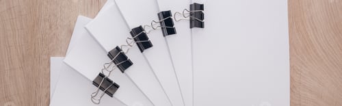 Preview: panoramic shot of stacks of blank paper with metal paper clips and copy space