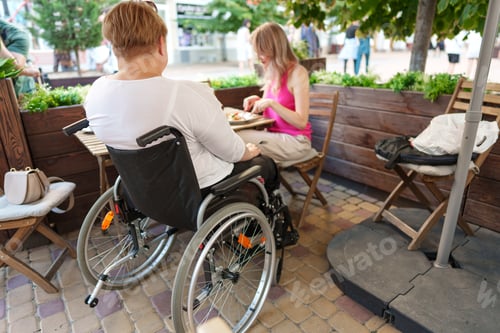 Preview: Woman wheelchair user dining at a restaurant with her young daughter.