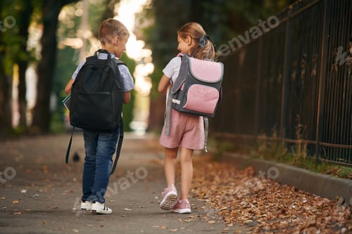 Preview: Young school children of boy and girl are together outdoors