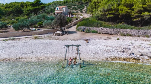 Preview: Relaxing on a tranquil beach swing at Brac Island, Croatia during a sunny summer day