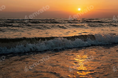 Preview: Colorful sunset on a sandy beach, waves with foam on the sand. Ocean, coast.