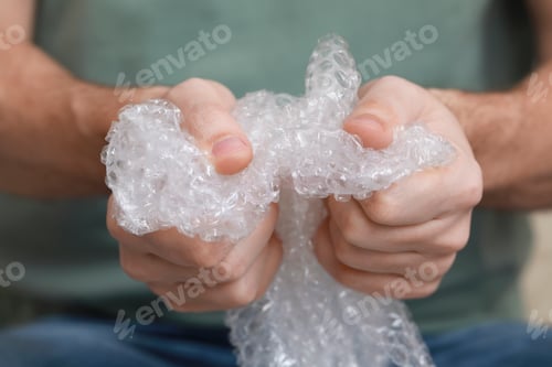 Preview: Man popping bubble wrap, closeup view. Stress relief