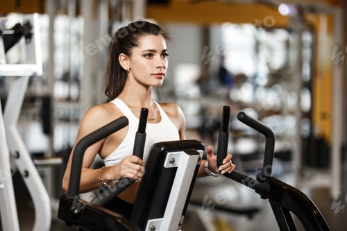 Preview: Young athletic girl dressed in sportswear doing exercises with special sport equipment in the modern