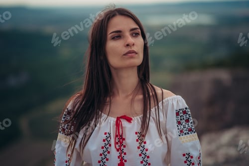 Preview: Atractive woman in traditional romanian costume on mountain green blurred background