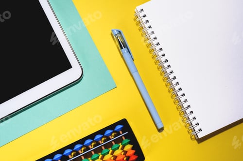 Preview: Close up flat lay with laptop, abacus, noteook and pen on yellow background.
