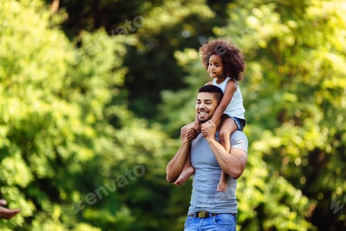 Preview: Portrait of young father carrying his daughter on his back