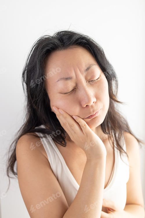 Preview: Young Asian girl touching mouth with hand with painful expression because of toothache or dental ill