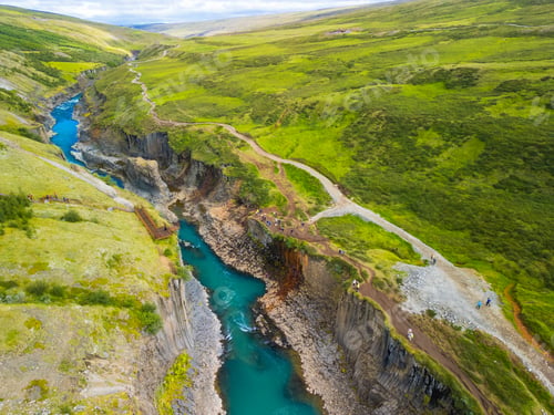 Preview: A scenic view of Studlagil Canyon in Iceland with basalt columns and a turquoise river.
