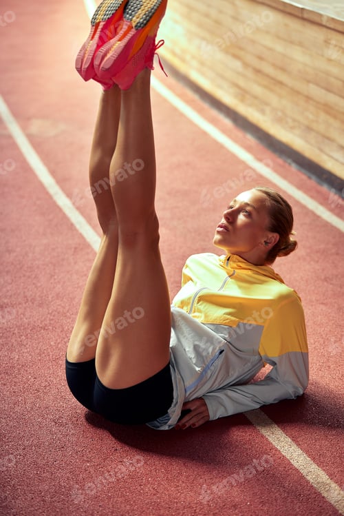 Preview: A young athlete girl is warming up before the race at the stadium. A slender blonde in a black