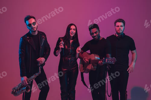 Preview: Group of young multiethnic musicians created band, dancing in neon light on pink background