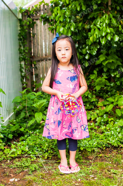 Preview: Portrait of serious young girl in garden with toy