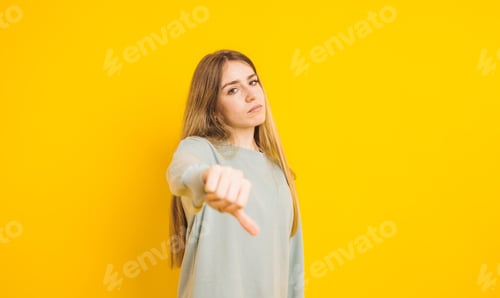 Preview: Woman Giving Thumbs Down on Yellow Background
