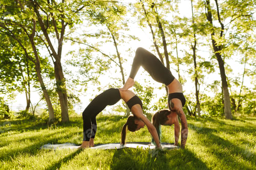 Preview: Two young ladies in black sporty tops and leggings training yoga poses together