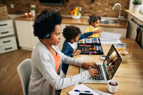 Preview: Black single mother using computer and making video call while working at home.