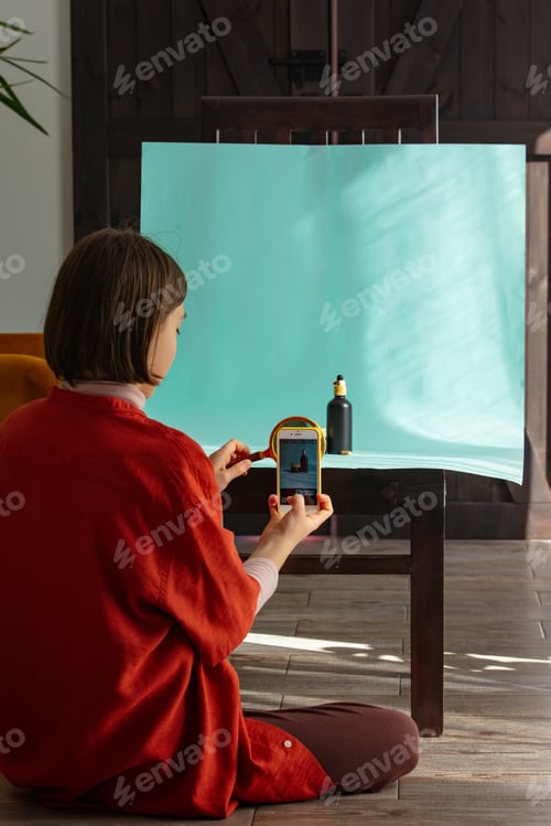 Preview: Stylish teenager ukrainian girl make a photo of perfume on blue background indoor at home