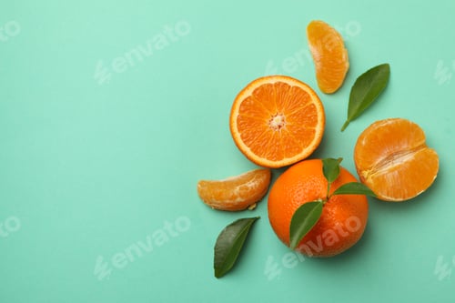 Preview: Ripe mandarins with leaves on mint background, top view