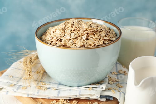 Preview: Composition with oatmeal flakes and milk on white table. Cooking breakfast