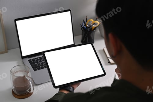 Preview: View over shoulder businessman sitting at office desk and using digital tablet.