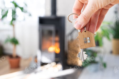 Visualização: Chave para casa com chaveiro contra fundo de lareira, fogão com fogo e lenha. Casa aconchegante h