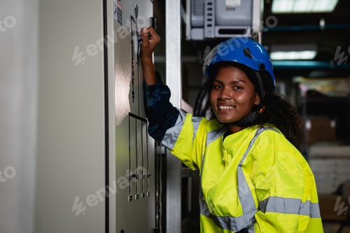 Preview: Technician in a yellow and blue safety vest is working on a panel