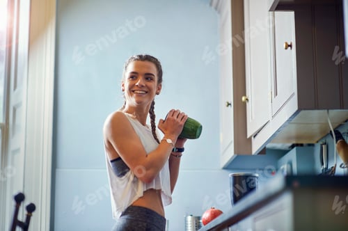 Preview: Young woman shaking juicer at kitchen counter