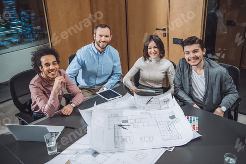 Preview: group of successful architects sitting at conference hall at office and looking at camera