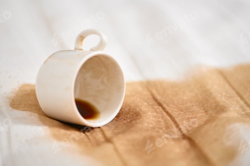 Preview: Overturned white cup with coffee spill on fabric surface