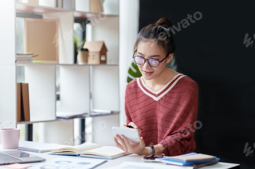 Preview: Asian businesswoman working with laptop computer using calculator to calculate business finance