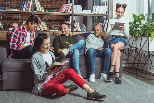 Preview: young multiethnic students with books and digital tablet studying together indoors