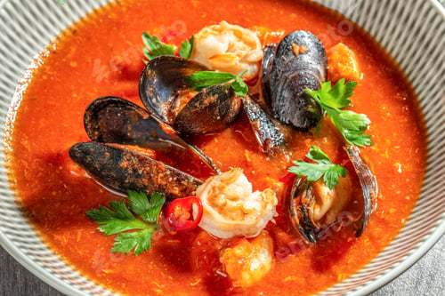 Preview: A close-up of a rich seafood soup with shrimp, mussels, red chili slices, and parsley