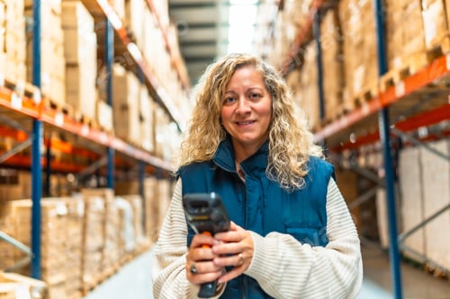 Preview: Woman holding a wireless scanner working in a distribution warehouse